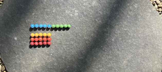 Colourful marbles, arranged on a mostly five by five grid. The first row is ten marbles wide, the second row is missing, it was moved from to the end of the first row.